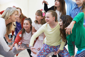 A group of children acting with a theater instructor.