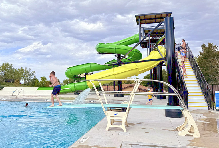 Diving pool with diving board, drop slide, and deck level flume slide.