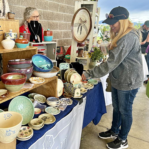 A woman viewing a display of pottery pieces.