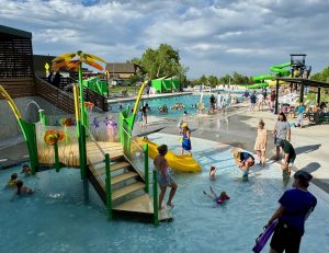 Patrons enjoying play feature and slides at 6th Avenue West Pool