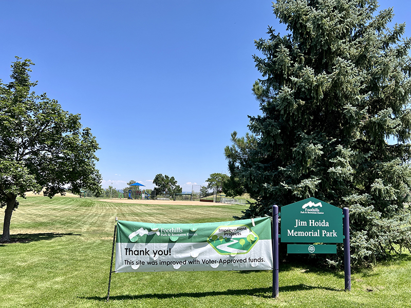 Entry sign for Jim Hoida Memorial Park with the park in the background.