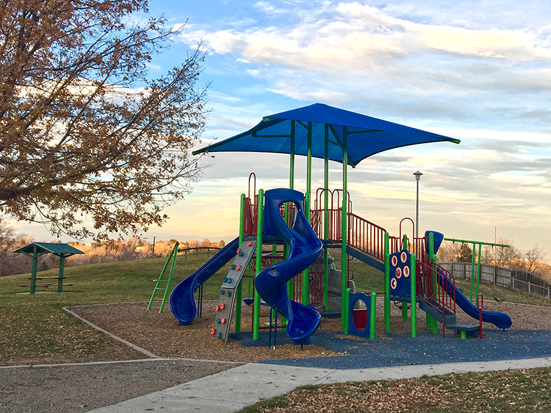 Playground with slides, climbers, swings and a shade structure.