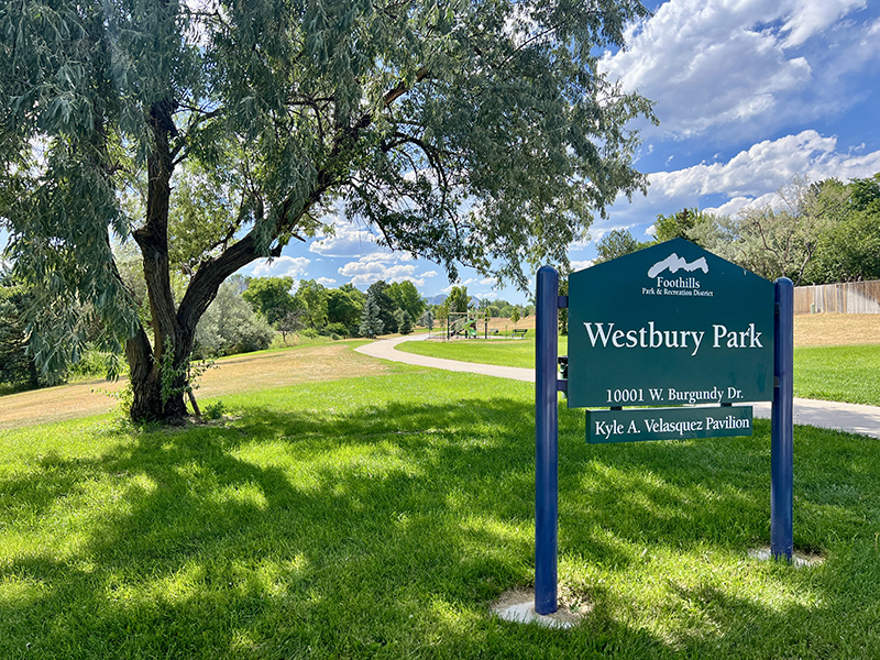 Park entrance sign reading Westbury Park with a meandering sidewalk trail.