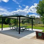 A park shelter with picnic tables and a memorial rock beside it.