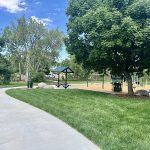 A meandering sidewalk leading to a playground a small picnic shelter.