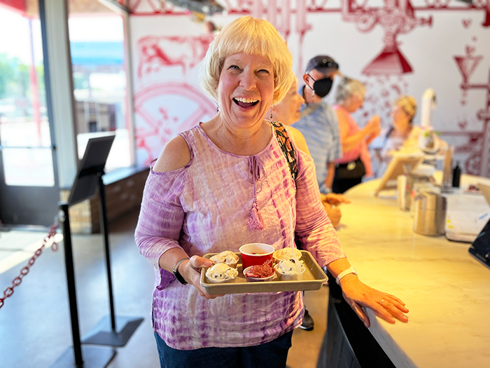 A woman smiling while holding a tray of ice cream samples.