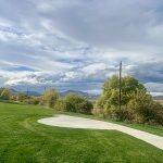 Park view of green grass, a sidewalk trail and mountains in the background.