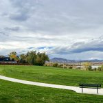 Park view with green grass, sidewalk, park benches.