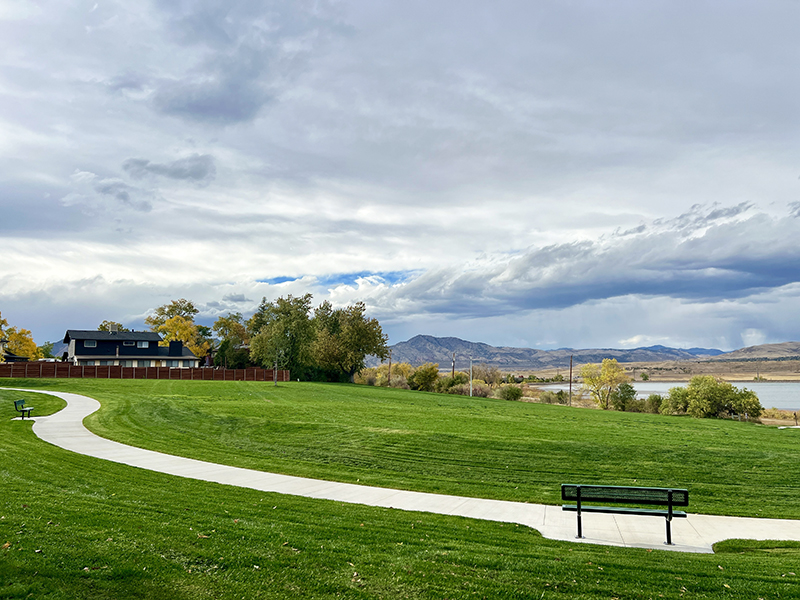 Park view with green grass, sidewalk, park benches.