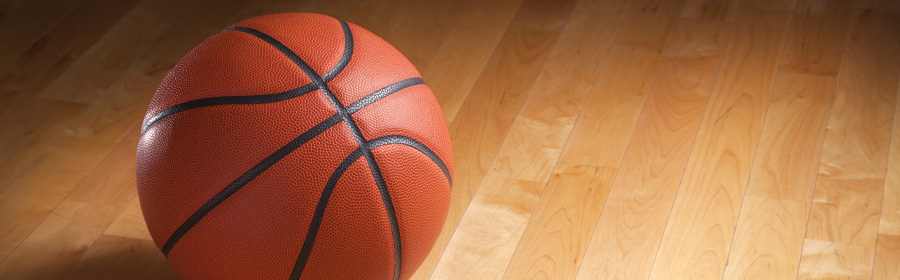 A basketball resting on a hard wood floor.